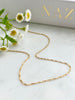 Gold filled Fine rope chain laying flat on marble with flowers and NAZ Parure Box in background