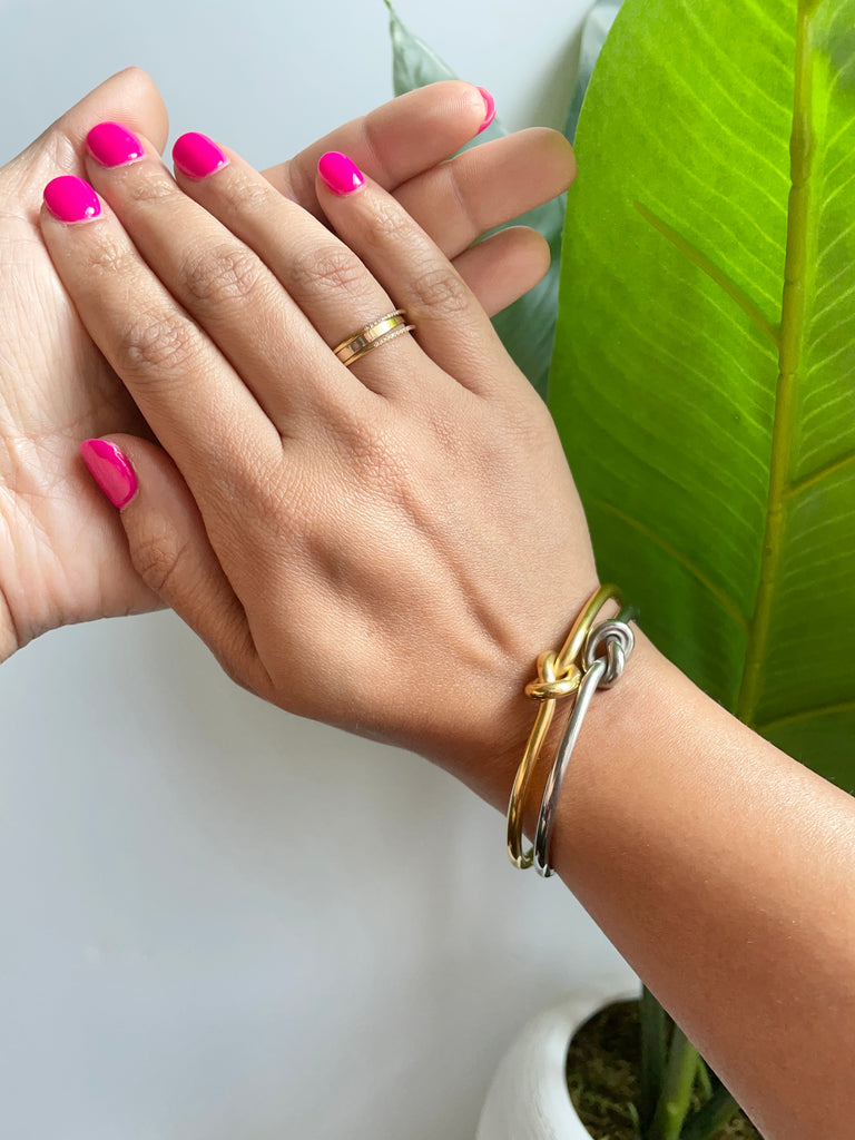 stainless steel and gold plated timeless knot cuff stacked on right wrist.