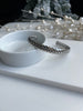 Gorgeous stainless steel wheat cuff bangle against white dish and pearl background.