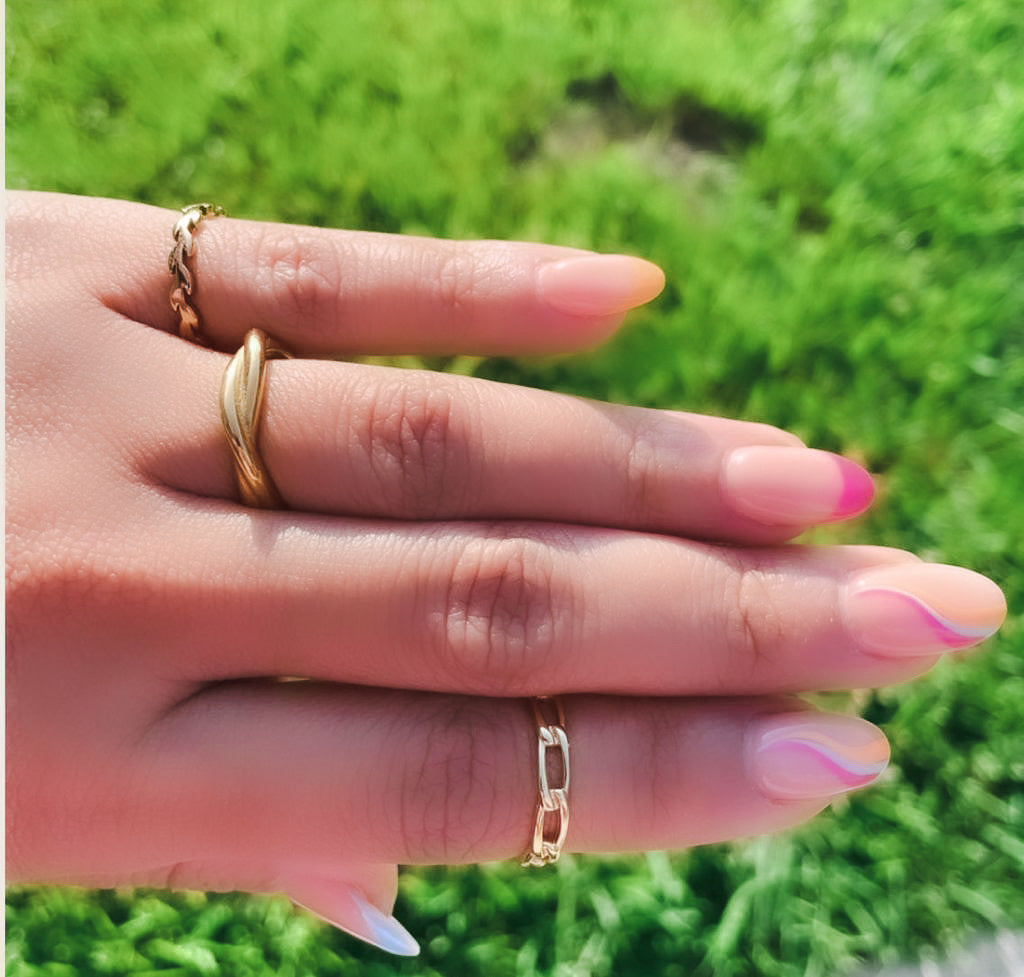 Woman with nail art wearing stack of rings including the Paperclip Chain Ring, Twist Ring & gold leaves ring from NAZ Parure.