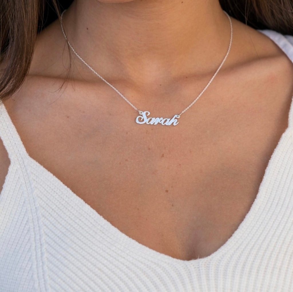woman in white tank top wearing personalized name necklace in sterling silver or solid white gold option.