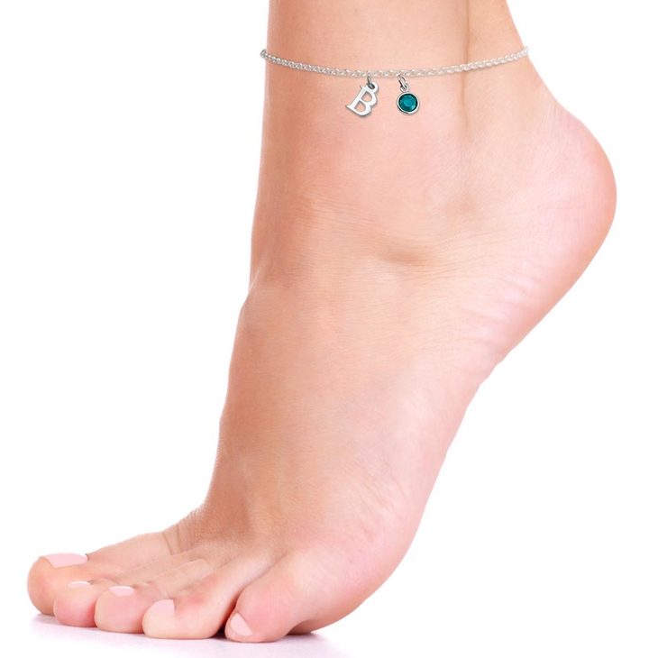 Personalized anklet with birthstone on a left foot.