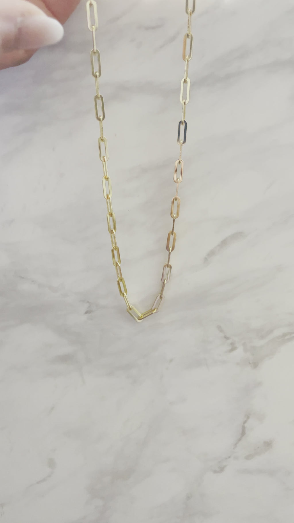 Shiny and elegant Gold Filled Paperclip Chain against a marble background.