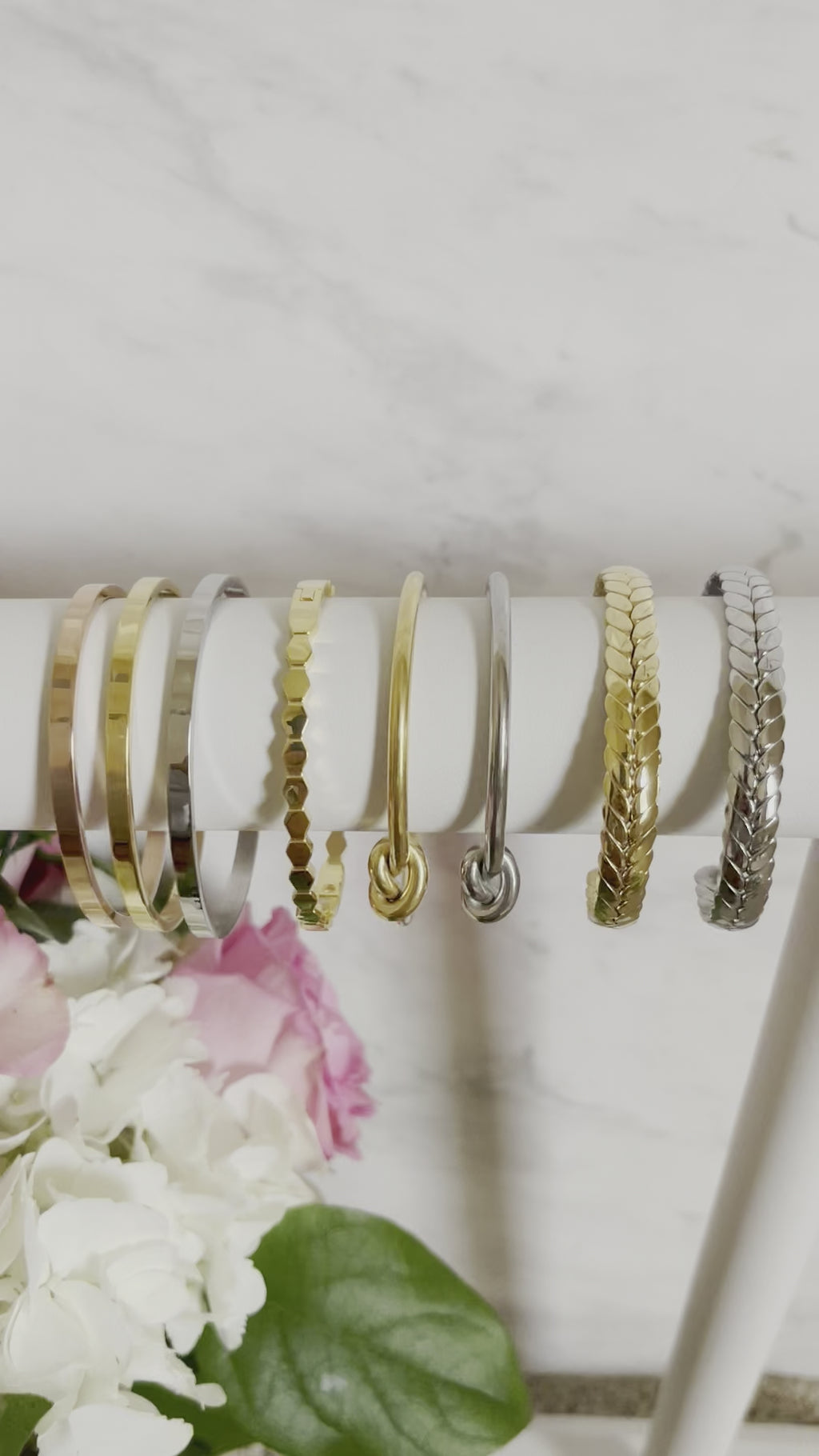 close up of stainless steel and gold plated timeless knot cuff along with other bangle options available through NAZ Parure jewelry.