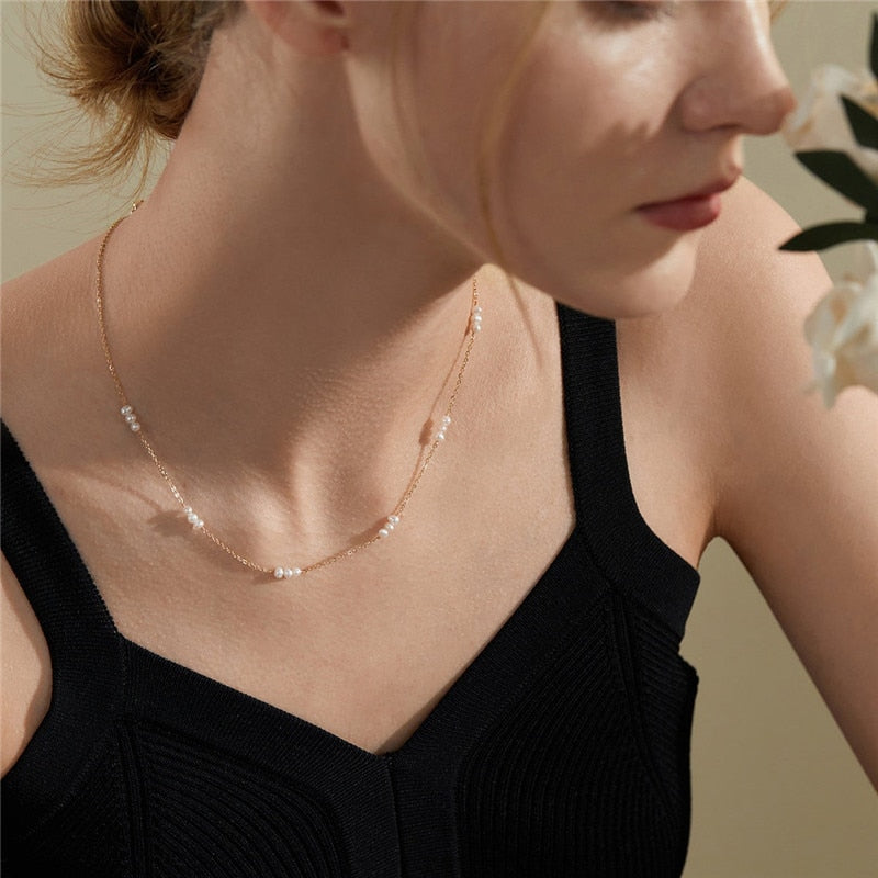 Woman with Black sleeveless dress wearing 14K Gold-Filled Pearl Pattern Necklace and smelling wedding flowers.