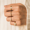 Woman with white sweater wearing gold filled infinity band stacked with several other rings.