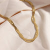 18K Gold Plated Braided Chain Necklace against a light colored satin fabric