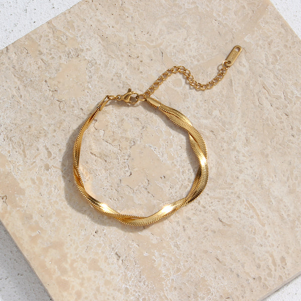 Gold Braided Chain Bracelet against stone background with sunlight shining.