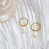 Elegant Pearl Drop Gold Hoops against a white satin fabric.