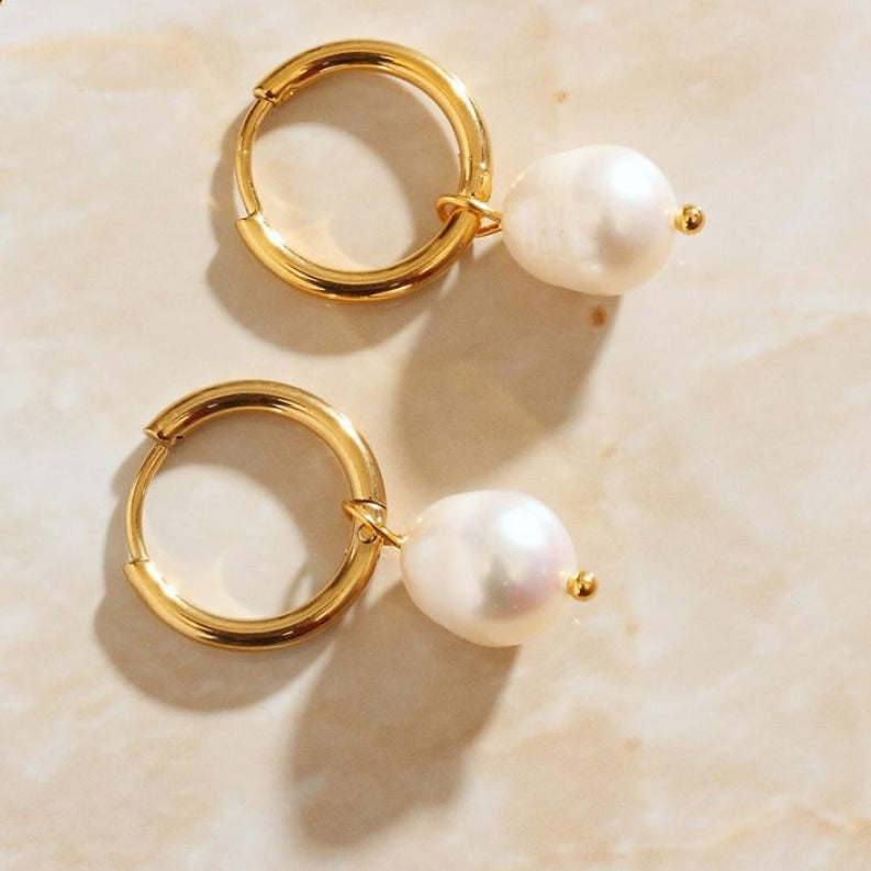 Close up of 18K gold plated Pearl Drop Gold Hoops against a marble background.