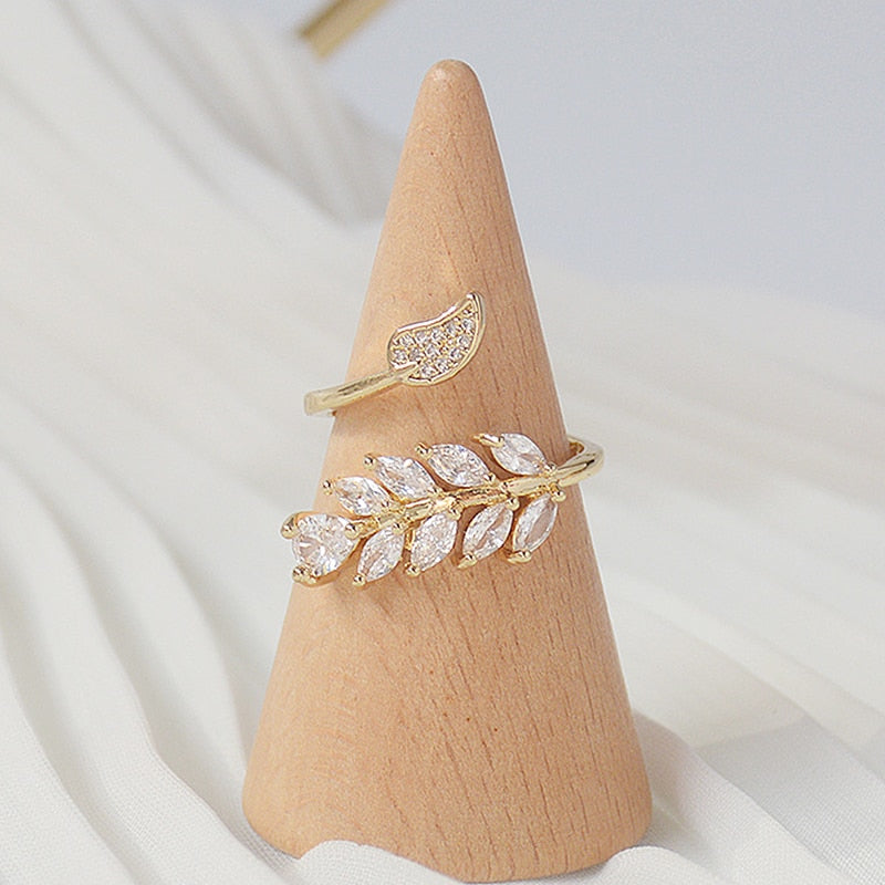 Gold Floral Leaf Ring on a ring stand with white background.