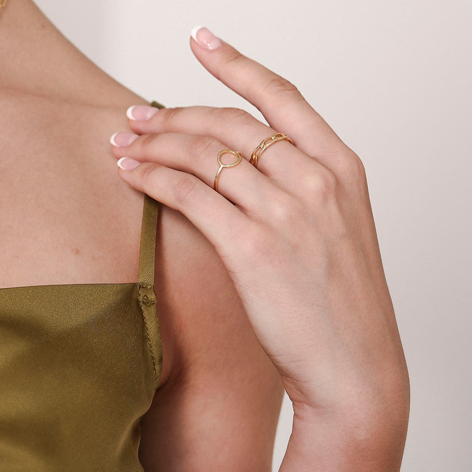 Woman in green thin strap wearing 18K gold plated Paperclip Chain Ring and Karma ring.