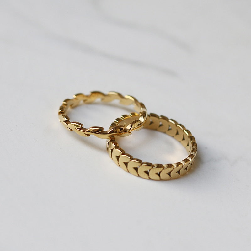 Gold Leaves Ring and Gold Wheat Ring from NAZ Parure stacked on a marble counter.