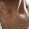 Woman with with low cut blouse stacking 14K Gold-Filled Oval Link Chain with longer necklace similar to 14K Gold-Filled Sunbeam Coin Necklace.