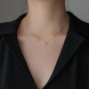 Woman with low cut black collared shirt wearing 18k gold plated Zirconia Pendant Necklace from NAZ Parure Jewelry.