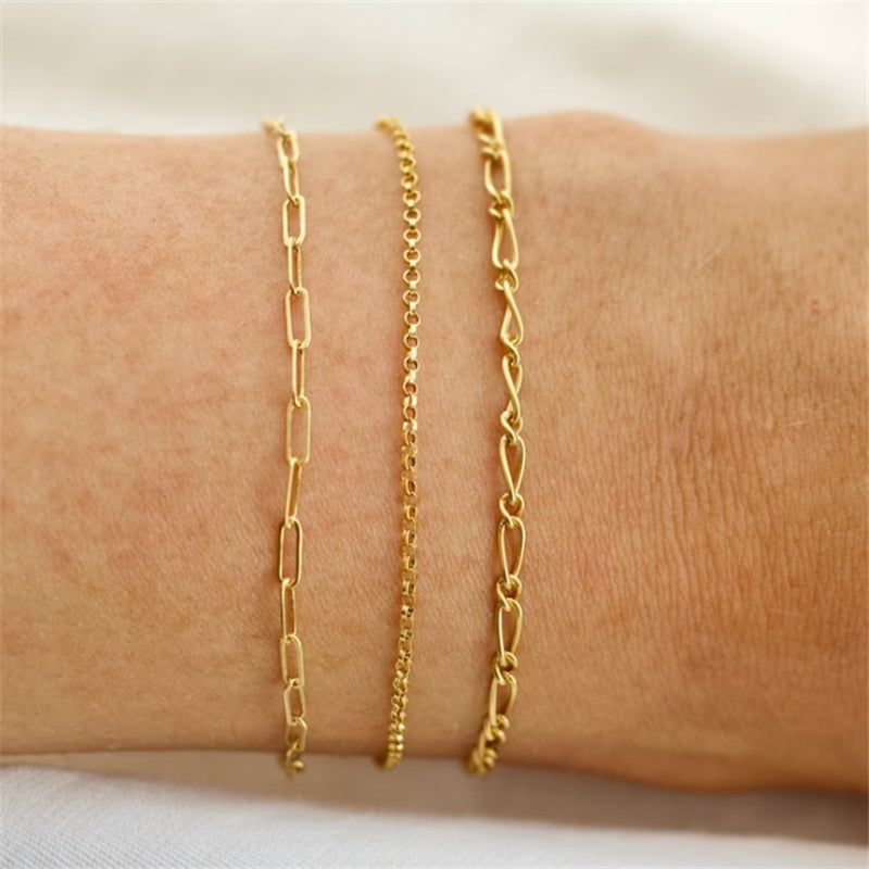 Woman wearing three gold filled bracelets on wrist including classic chain link bracelet.