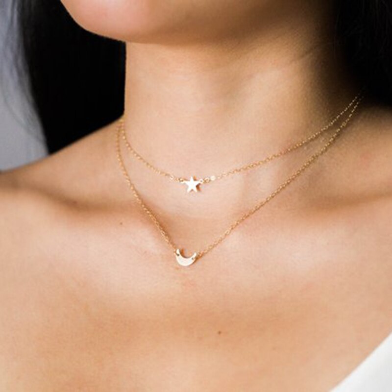 Woman wearing 14K gold filled celestial moon and star necklace on low cut white blouse.