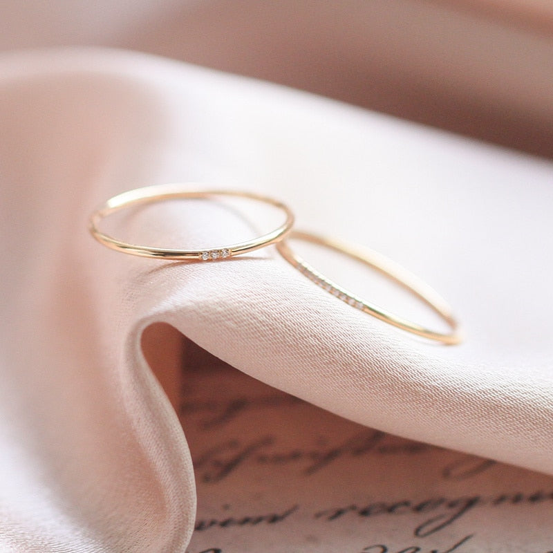 Two 14K gold filled thin studded rings laying on white fabric.
