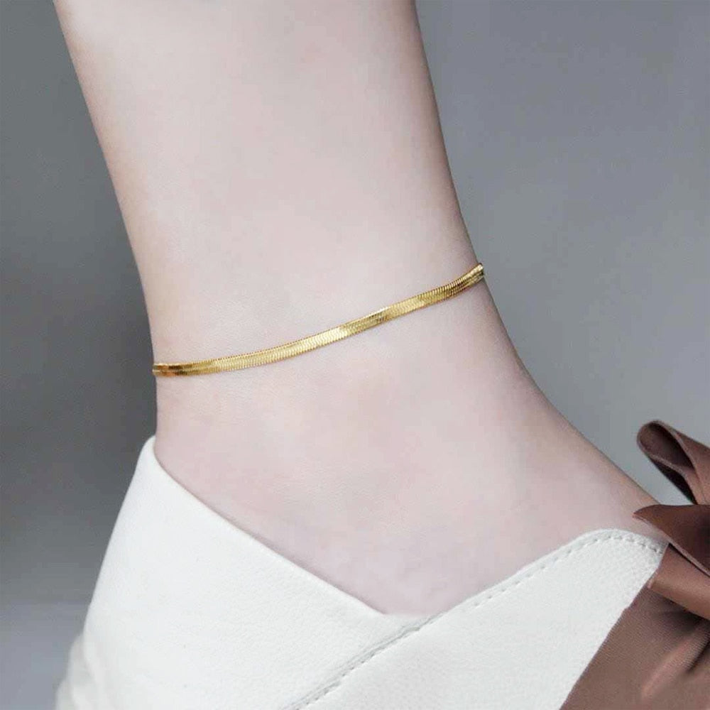 Woman in trendy sneakers wearing 18K gold vacuum plated Herringbone Anklet from NAZ Parure Jewelry.