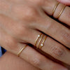 Multiple delicate and dainty 14K gold-filled rings stacked on hand. 