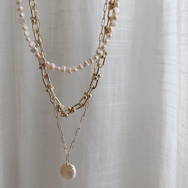 Hanging view of Shell Drop Paperclip Chain, Parure of Pearls choker & Bold Gold Chain from NAZ Parure Jewelry. 