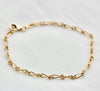 14K gold filled Classic Chain Link Bracelet on white fabric. 