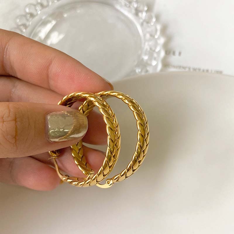 Woman with chrome nails holding Gold Wheat Hoops in a close up.