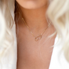 Woman with white low cut blouse wearing 14K gold filled Infinity necklace. 