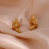 Timeless Knot Gold Studs on satin fabric.