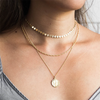 Woman with low cut gray shirt wearing stacked 14K gold-filled necklaces 