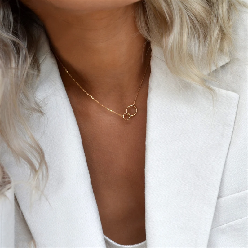 woman with low cut blouse and white blazer wearing 14K gold filled infinity necklace.