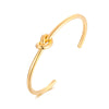Gold plated Timeless Knot Cuff Bangle against white background.
