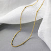 Close up of 18K gold plated & waterproof Thin Beaded Choker against white cloth.