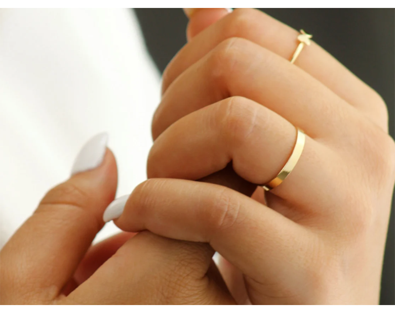 Woman with white nails wearing 14K gold filled infinity band as wedding ring.