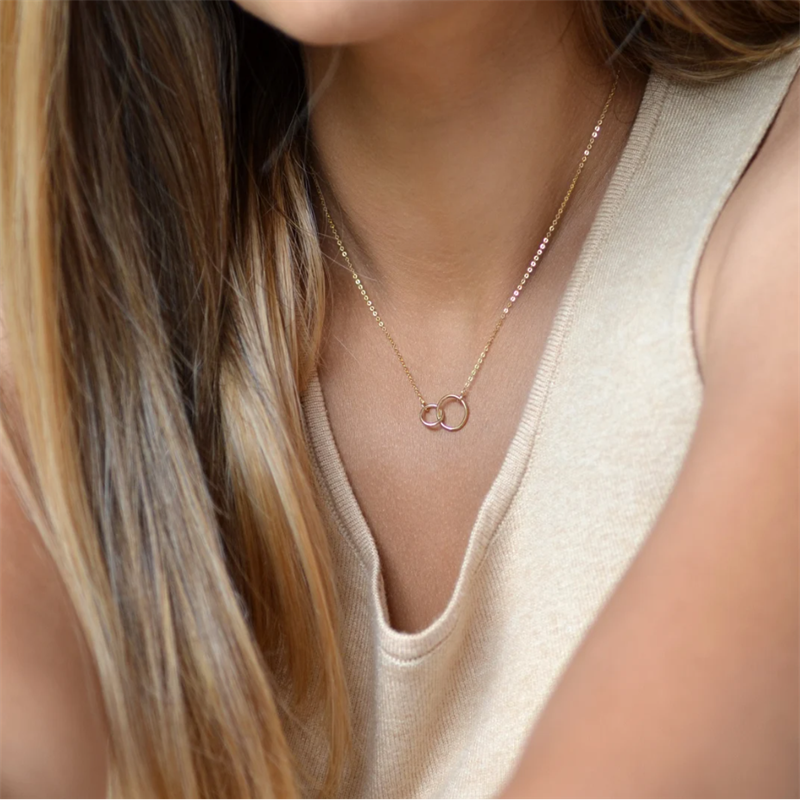 Woman with cream tank top wearing 14k Gold filled Infinity Necklace. 