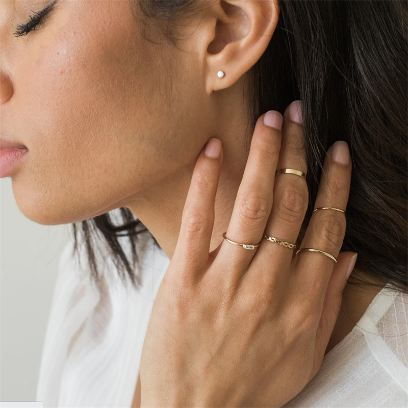 Woman in white blouse with stacked Gold-Filled rings including the Thin Braid Ring, the Simply Thin Ring and the Infinity Band.