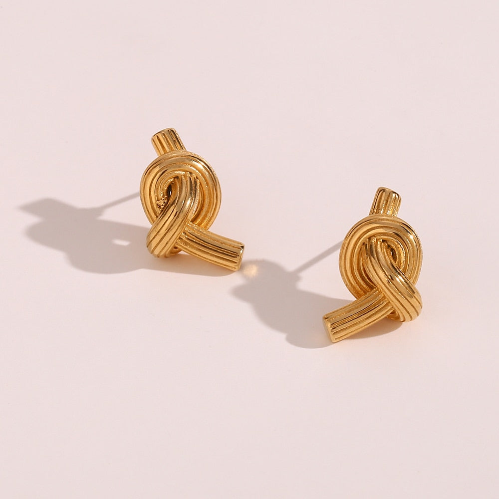 Timeless Knot Gold Studs casting shadow on white background.