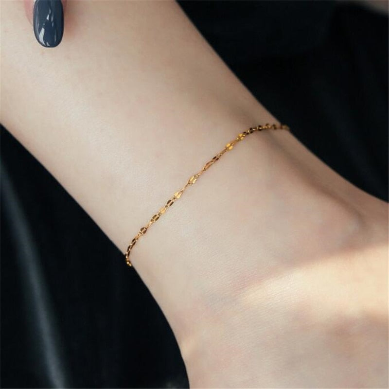Woman wearing 18K gold plated Heart Chain Anklet while barefoot.