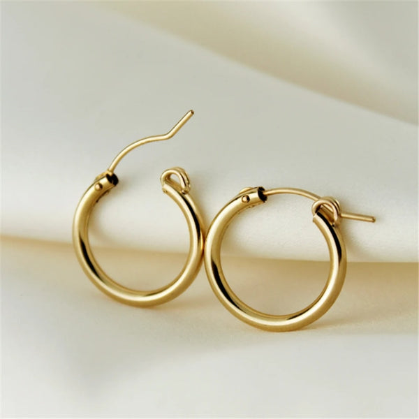 14K gold filled Simply Me Hoops resting on white fabric with one clasp open.