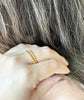 Woman stacking thin and thick Beads of Gold Ring on middle finger.