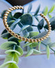 Gold filled twist rope bangle resting on greenery.