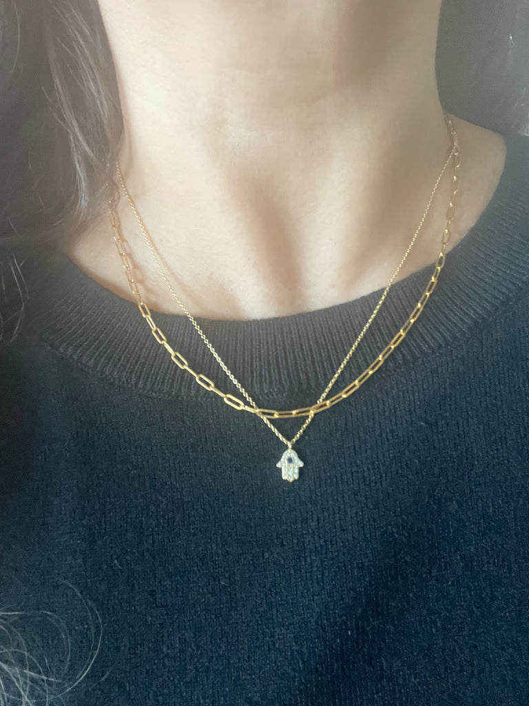 Woman in Black sweater wearing Gold FIlled Oval Link Chain and Gold Plated Hamsa Necklace from NAZ Parure Jewelry.