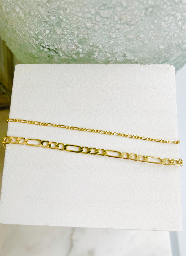 Thin and Classic 18K Gold Filled Figaro Chain on white wooden block.
