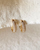 14K Gold FIlled Zirconia Oval Huggies hanging on fabric.