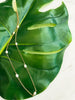14K Gold Filled Single Pearl Pattern Necklace resting over green palm leaf.