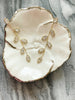 Gold Leaves on Vine Earrings on a porcelain dish with a marble background.